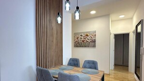 Un espace de salle à manger moderne avec une table en bois, des chaises à revêtement gris et des luminaires suspendus.