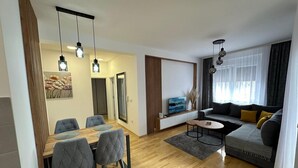 Un salon moderne comprenant un canapé, une table basse et un coin repas avec des chaises.