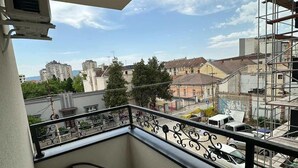 Un balcon avec une table et des chaises, une vue sur le paysage urbain et une structure d’échafaudage.