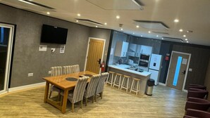 A modern hotel room with a dining area, kitchen, and a TV mounted on the wall. - Heart of Hull Hotel (Hull)