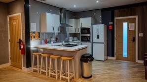 A modern kitchen with a central island, bar stools, a trash bin, and a fire extinguisher. - Heart of Hull Hotel (Hull)