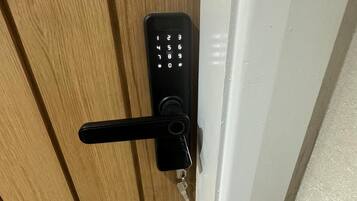 En trædør med en sort elektronisk keypad-lås og en nøgle i låset.