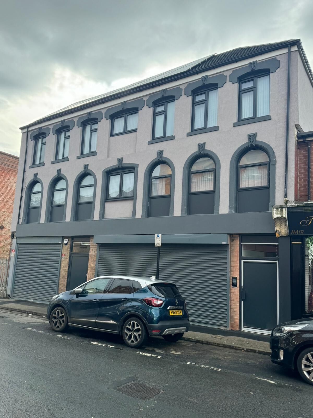 A two-story building with a garage door and a parked car.