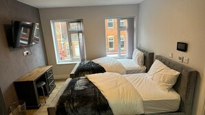 A bedroom with a bed, a desk, a TV, and two windows. - Heart of Hull Hotel (Hull)