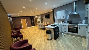 A modern hotel room with a kitchen, a dining area, and a seating area with chairs. - Heart of Hull Hotel (Hull)