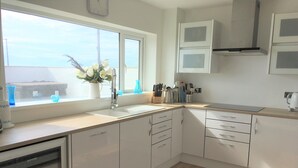 Une cuisine avec des meubles blancs, une fenêtre donnant sur un beau paysage et un évier.