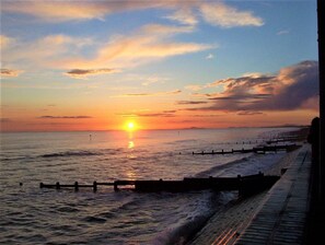 Un atardecer sobre un mar tranquilo con un muelle de madera que se adentra en el agua.