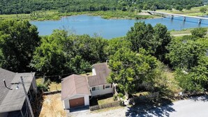 A residential area with a large body of water, a bridge, and houses with sloped roofs. - Lake Views! Little Bell Bungalow Charmer, Backyard, Game Room, Foosball (Forsyth)