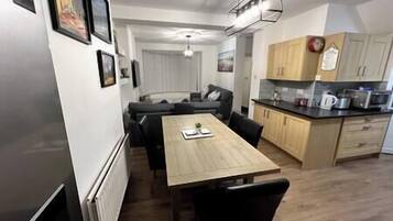 Eine kompakte Küche mit Holzschränken, einem Esstisch mit Stühlen und einem Kühlschrank.