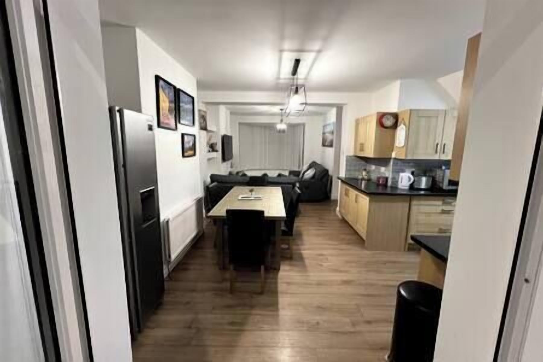 A compact kitchen with a dining area, wooden flooring, and white walls.