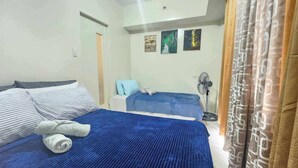 Un dormitorio con dos camas, un ventilador de pie y obras de arte en la pared.