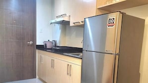 Una cocina con un refrigerador de acero inoxidable, armarios de madera y una encimera negra.