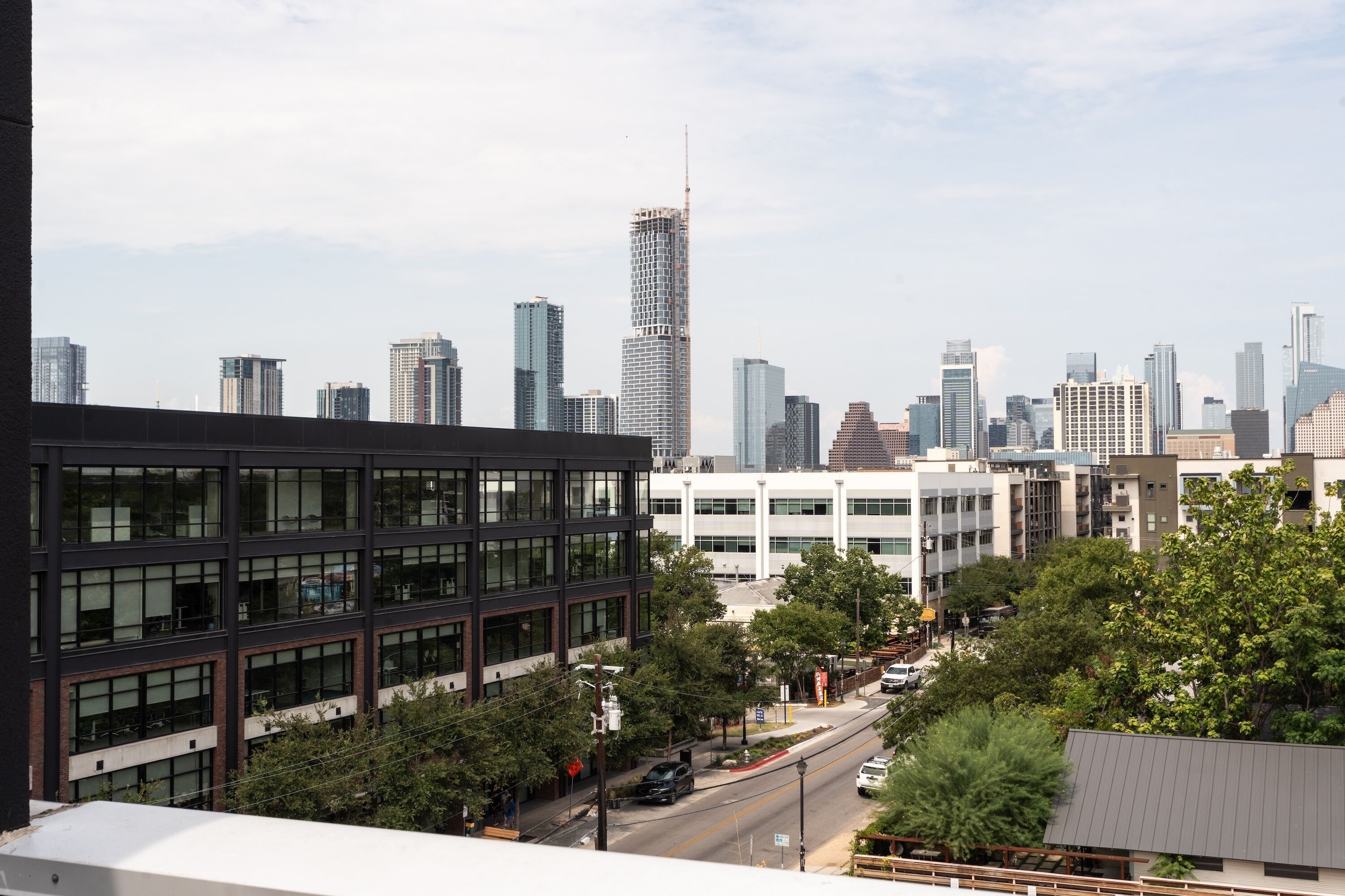 A cityscape with modern buildings, including a prominent skyscraper under construction.