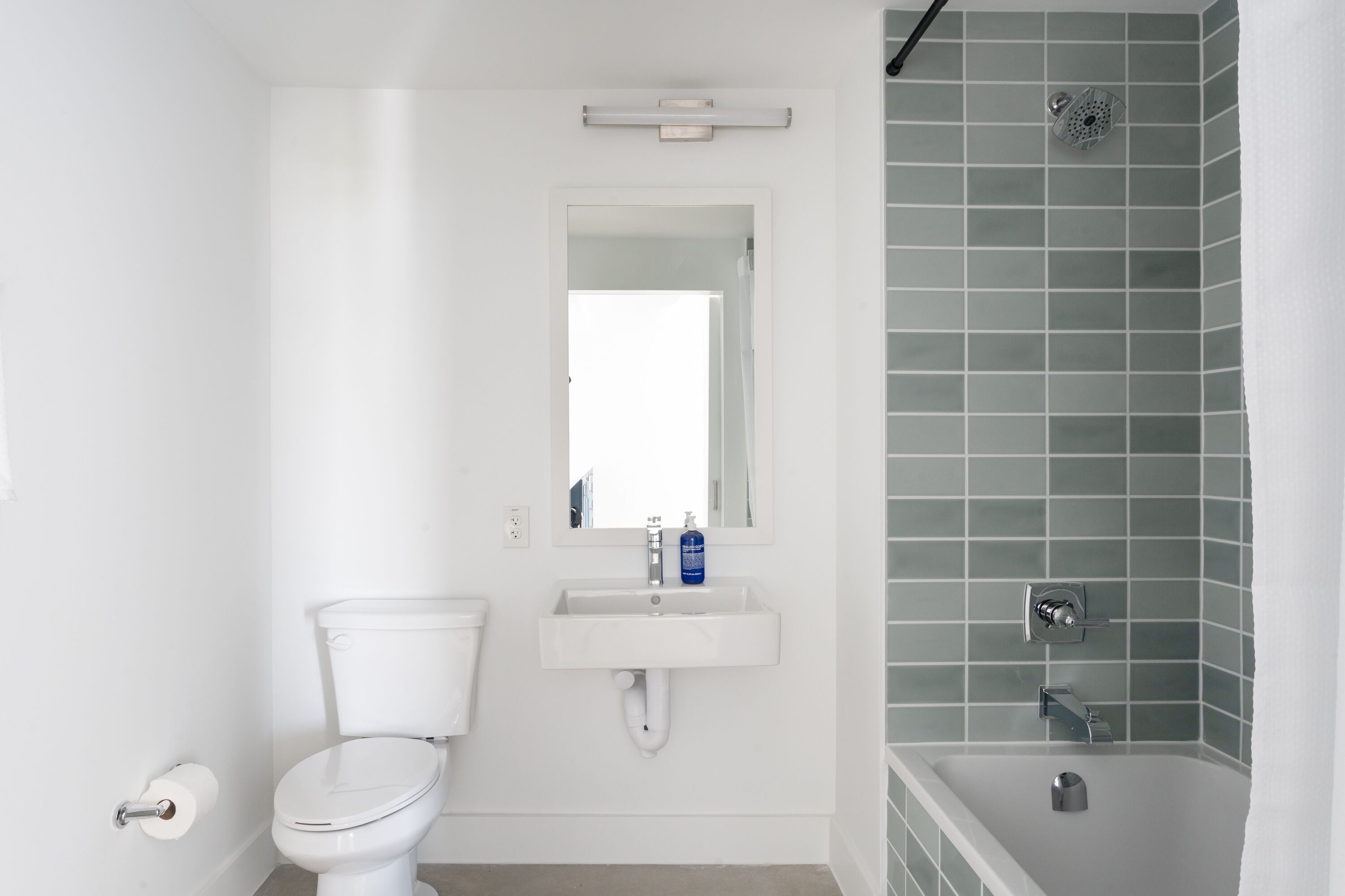 Une salle de bain comprenant des toilettes, un lavabo, un miroir et un espace douche.