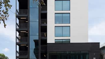 Un bâtiment moderne à plusieurs étages, doté d’une façade en verre, d’une entrée bien visible et d’un parking situé à l’avant.