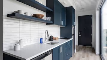 A modern kitchen with white subway tiles, a stainless steel sink, and dark blue cabinets.