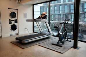A gym with a treadmill, stationary bike, and washing machines. - Studio Haus East 6th Austin by Kasa (Austin)