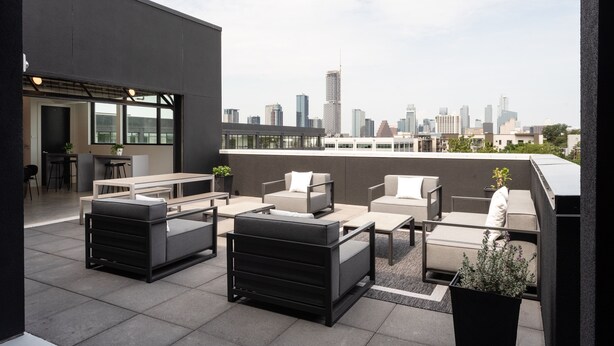 A rooftop terrace with modern outdoor furniture, a bar area, and a city skyline view. -  Studio Haus East 6th Austin by Kasa (Austin)
