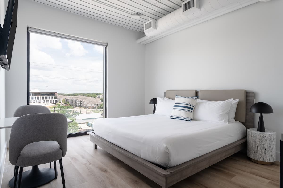 Un dormitorio moderno con una cama grande, un escritorio y una silla.
