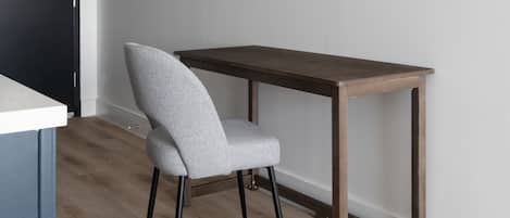 Ein modernes Zimmer mit einem grau gepolsterten Sessel, einem Holztisch und einem Holzboden.