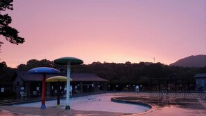 Zona de piscina con sombrillas de colores, un tobogán y una valla perimetral.
