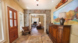 A spacious hallway with a wooden door, a stone wall, a rug, and a painting on the wall. - Crab Orchard Estate in Valle Crucis w/ Fireplace (Valle Crucis)