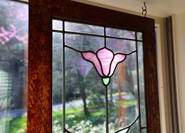 A stained glass window with a floral design, set in a wooden frame.