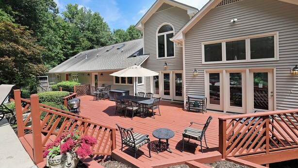 A two-story house with a covered patio area featuring outdoor furniture and a wooden deck. - Lg Pool House w/ Hot Tub Central to RTP*Pool OPEN* (Durham)