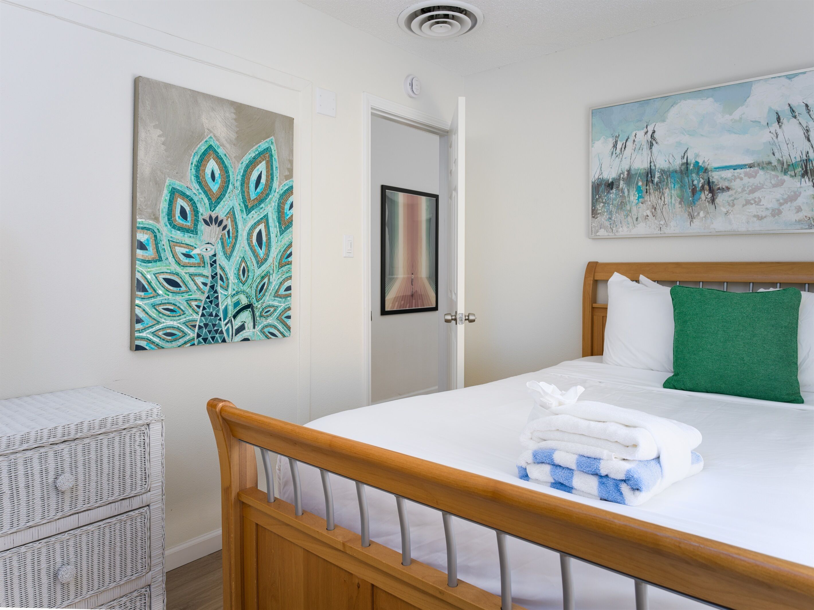 Un dormitorio con cama, una puerta y dos cuadros en la pared.