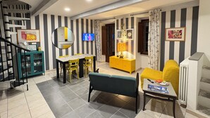 A living room with a dining area, a staircase, and a TV mounted on the wall.