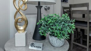 A lamp, a decorative sculpture, a potted plant, and a 'No Smoking' sign on a table. - Central Buckhead 2BR apartment with king beds, full kitchen, fast Wi-Fi, and free parking — minutes from Lenox Square, Phipps Plaza, and top dining. (Atlanta)