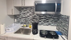 A kitchen with white cabinets, a stainless steel microwave, a coffee maker, and a gas stove. - Devonshire Cozy Haven (Winnipeg)