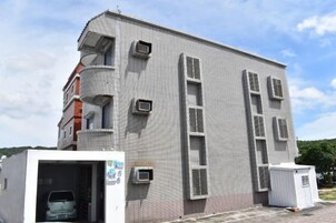 Un edificio de varios pisos con fachada plana, unidades de aire acondicionado y puerta de garaje.