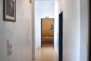 A narrow hallway leading to a room with a bed, a framed picture on the wall, and a door on the right. - Greenisland XD B&B (Taitung)