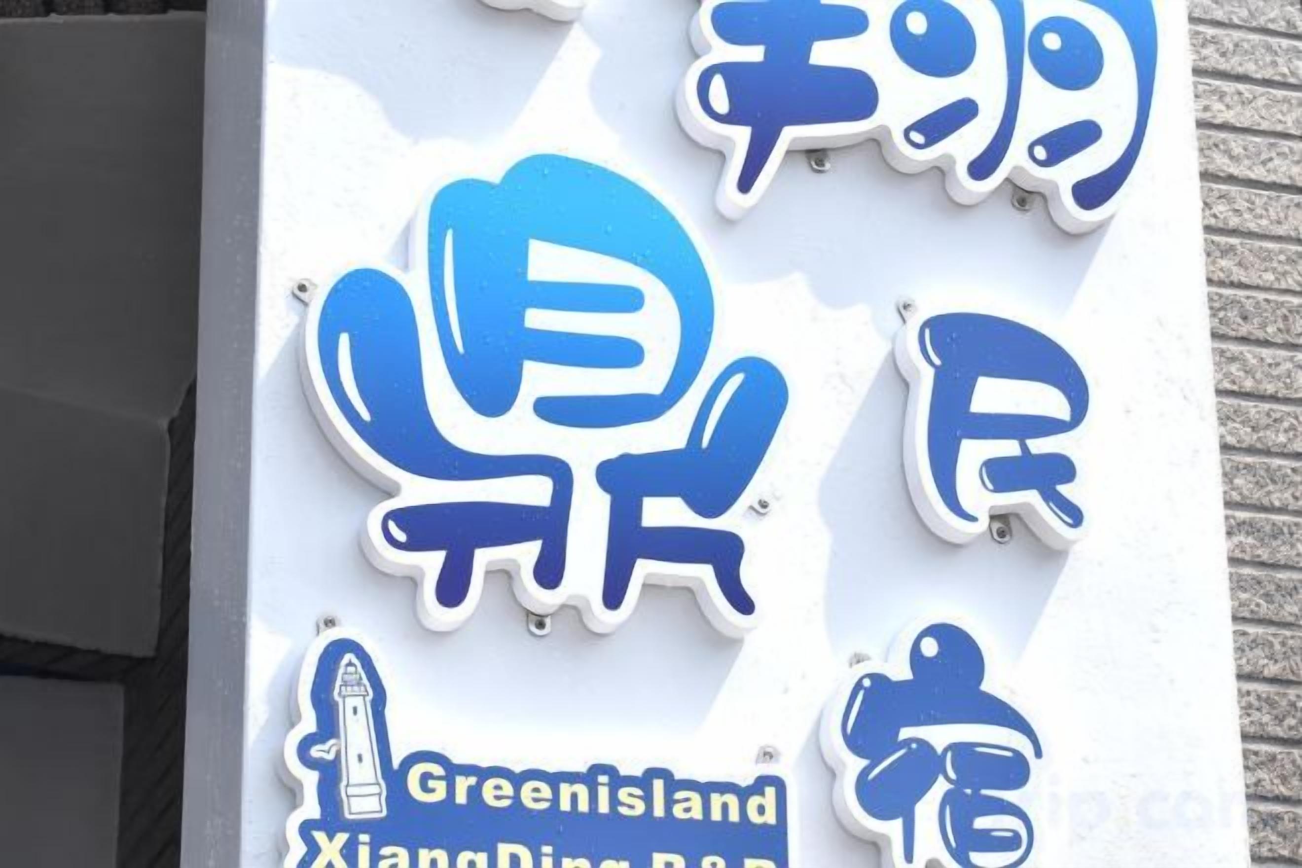 A sign with blue and white text, including the words 'Greenland XiangDing Ban' and a graphic of a person.