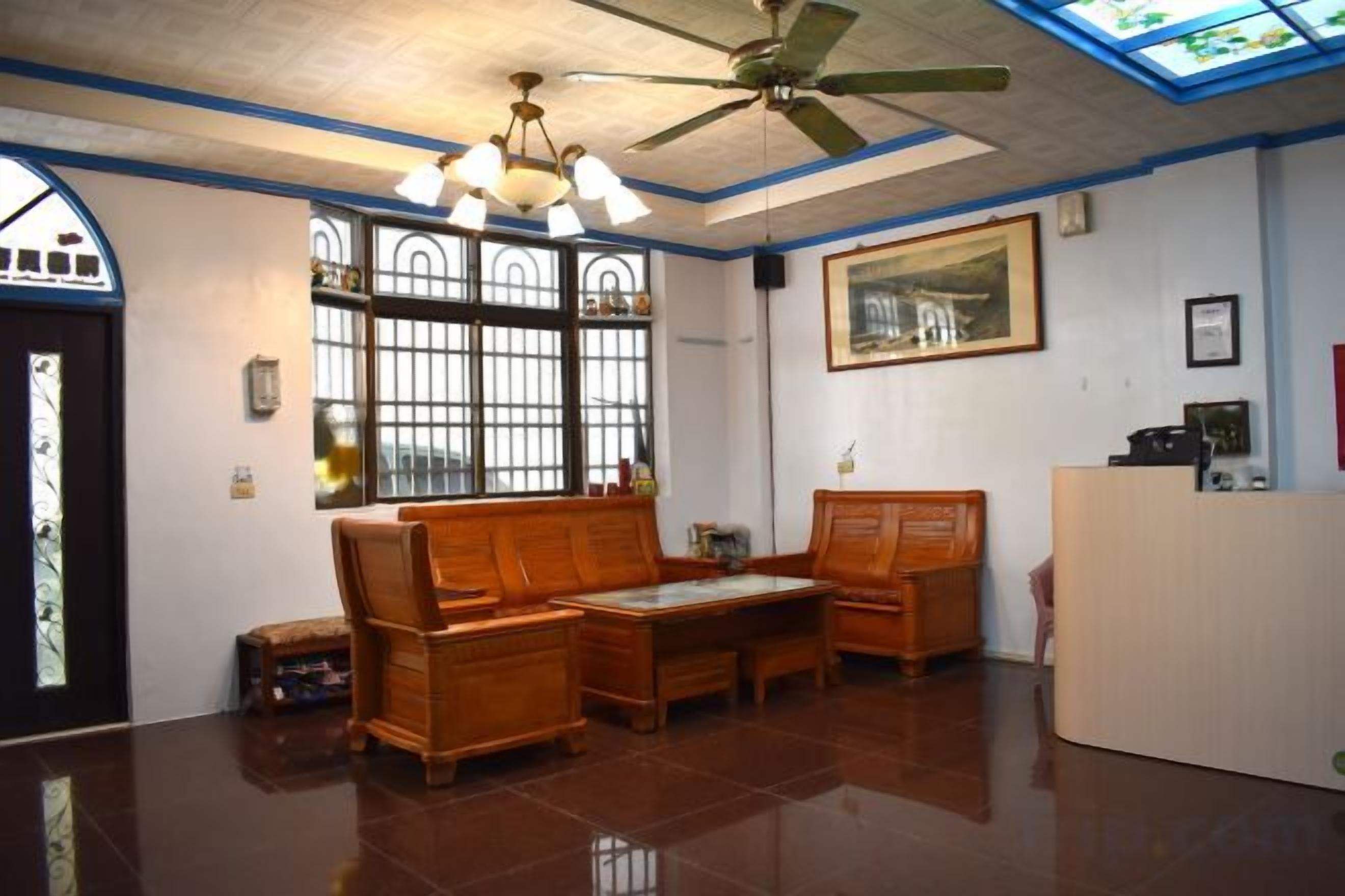A reception area with a ceiling fan, a reception desk, and a seating area with a bench and a table.
