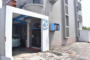 Un edificio con entrada de garaje, un toldo azul y una pared blanca con una ventana.