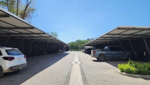 A parking area with covered carports, a paved walkway, and parked vehicles. - CASA MOLLY - 2 BEDROOM 2 BATHROOM MODERN APARTMENT - 5 MIN DRIVING TO THE BEACH (Nicoya)