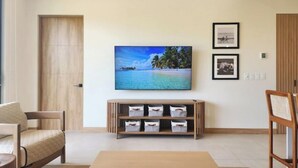 A living room with a flat-screen TV mounted on the wall, a wooden entertainment unit below it, and a large window on the left. - C14 - les Domus

 (Nicoya)