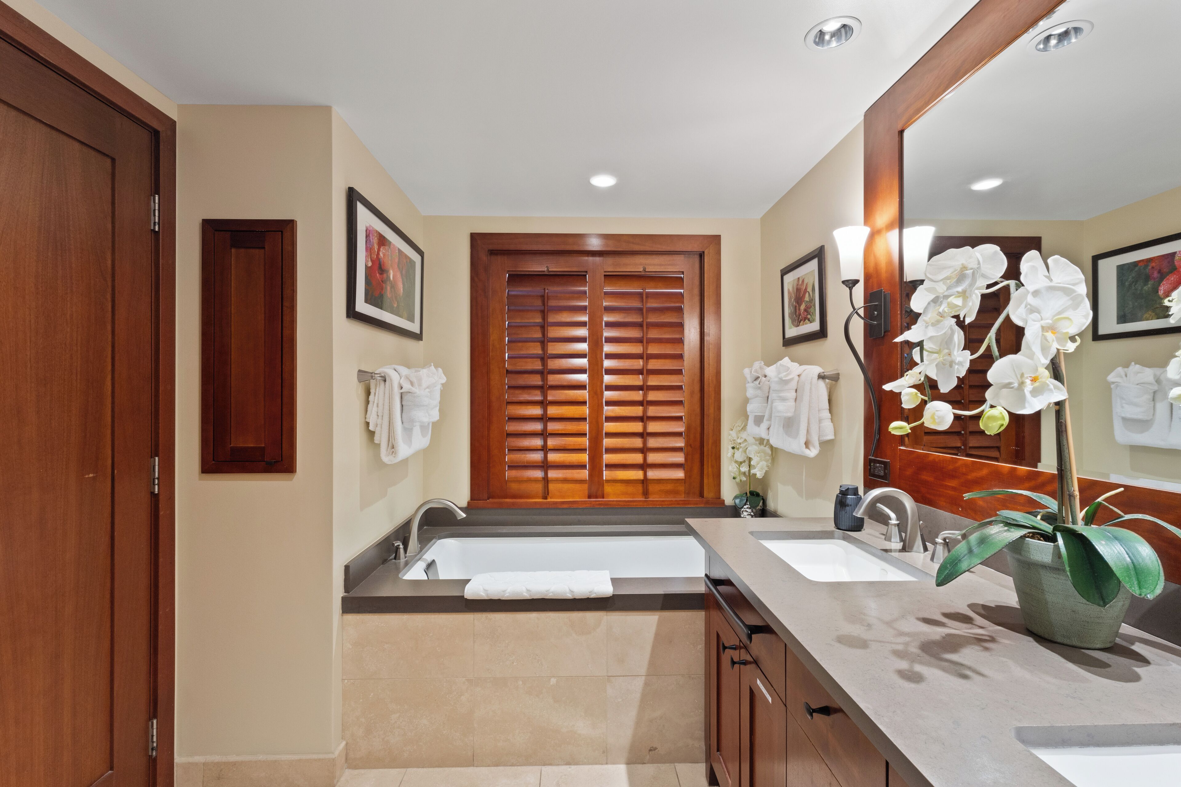 A bathroom with two sinks, a large mirror, and a potted orchid.