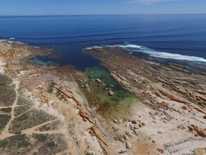 An aerial view of a coastal landscape with rocky terrain and clear blue waters.