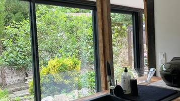 Une cuisine dotée d’un plan de travail en bois, d’un évier noir et d’une fenêtre donnant sur un paysage verdoyant.