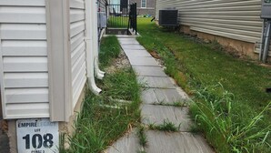 A narrow pathway leading to a house with a sign indicating "EMPIRE LEGACY LOT 108 PHASE 3".