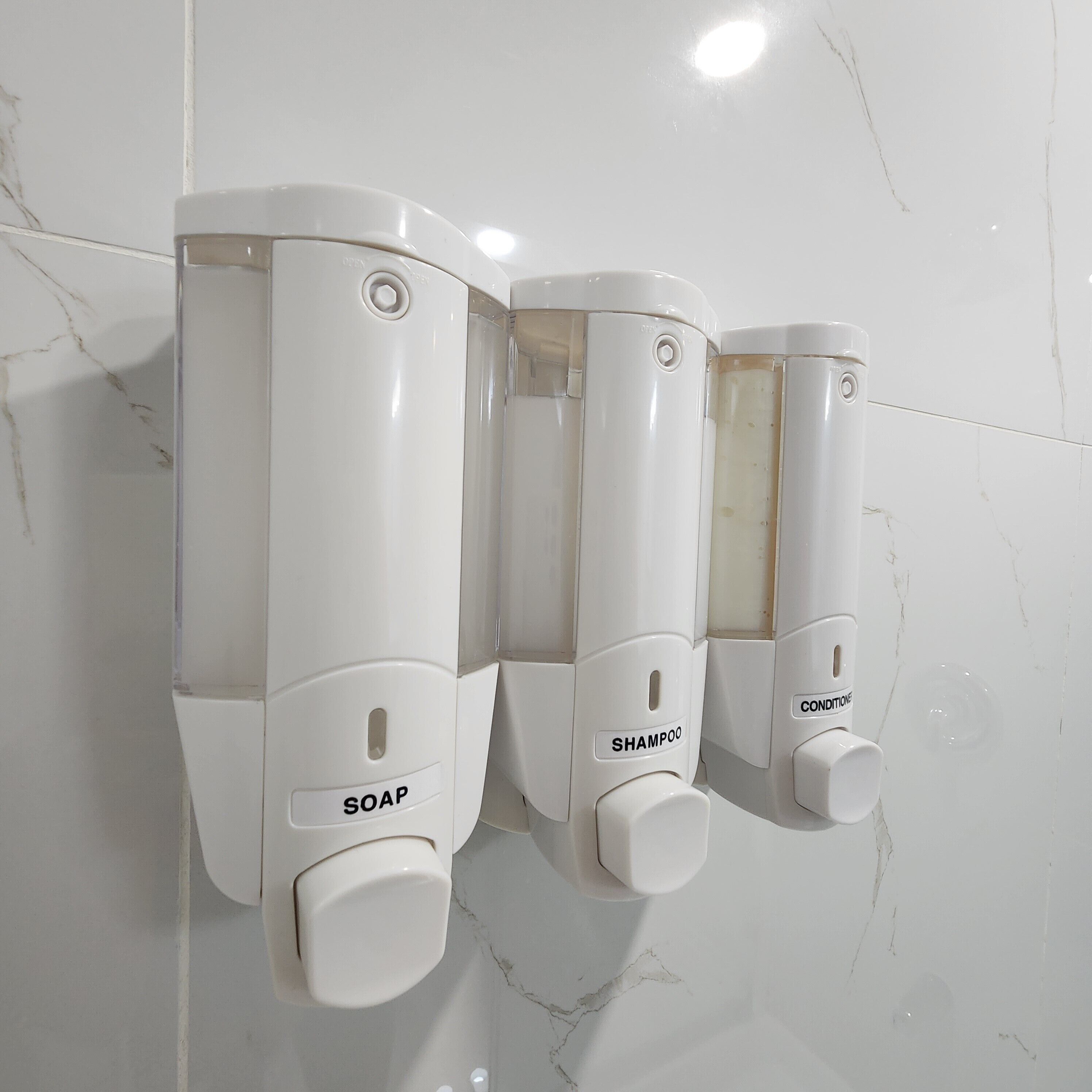 En väggmonterad tvåldispenser med en knapp för tvål och en knapp för schampo.