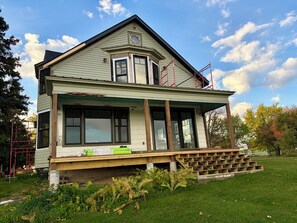 A two-story house with a covered porch and a small deck.