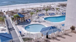 A rooftop pool area with two pools, lounge chairs, and a view of the beach.