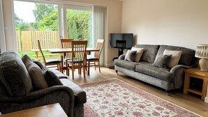 Ein Wohnzimmer mit einer Couch, einem Couchtisch, einem Fernseher und einem Essbereich mit Stühlen und einem Tisch.