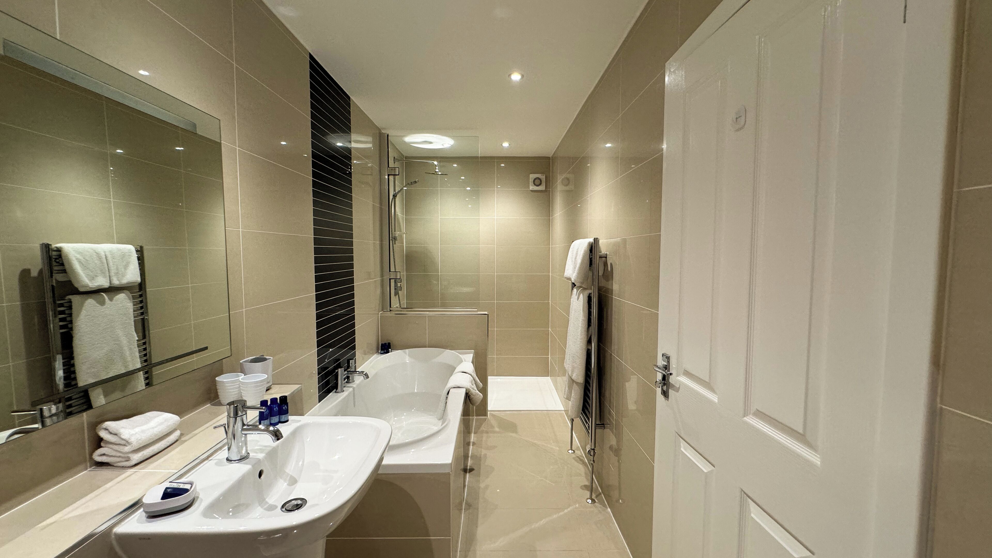 A modern bathroom with two sinks, a bathtub, and a shower.