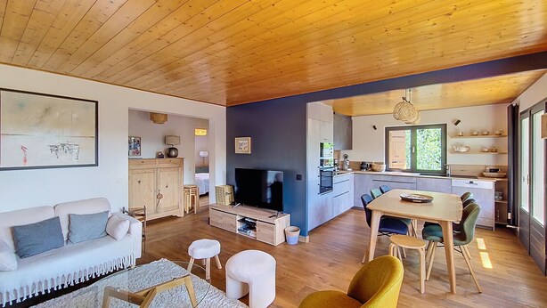 A modern living room with a sofa, TV, and dining area.