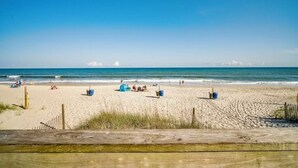 Ein Strand mit einem hölzernen Steg, der zum Ufer führt, bewölkter Himmel und ruhiges Meer.